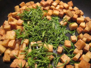 Pan-fried tofu cubes with black greasewood leaves.